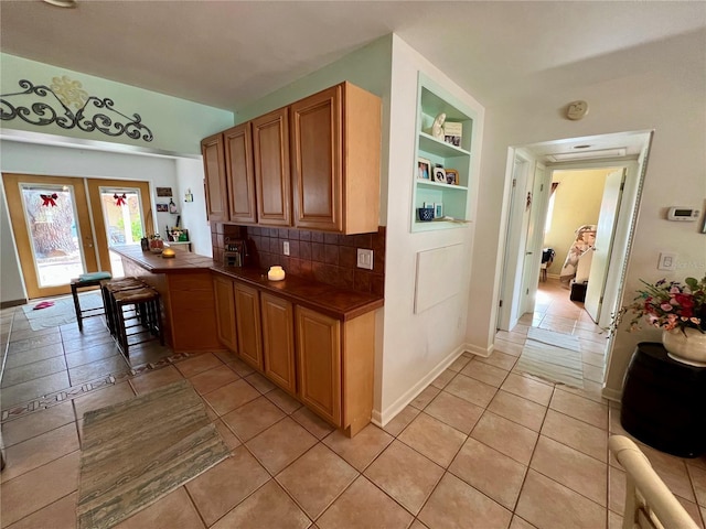 kitchen with backsplash, built in features, and light tile patterned flooring