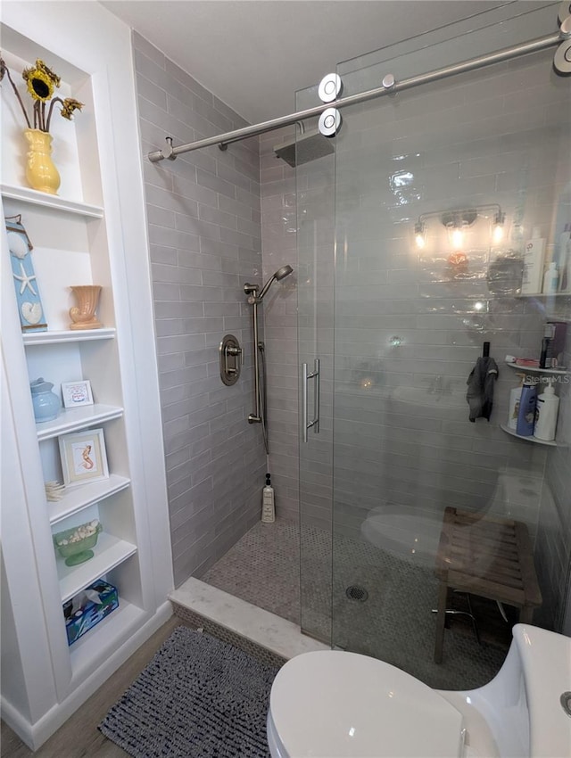 bathroom with hardwood / wood-style flooring, built in shelves, toilet, and walk in shower