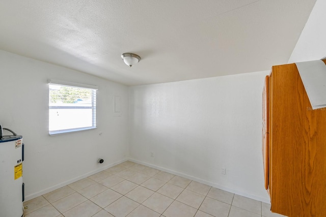 spare room featuring lofted ceiling, light tile patterned floors, a textured ceiling, and electric water heater