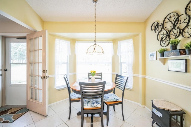 tiled dining room with french doors and a textured ceiling