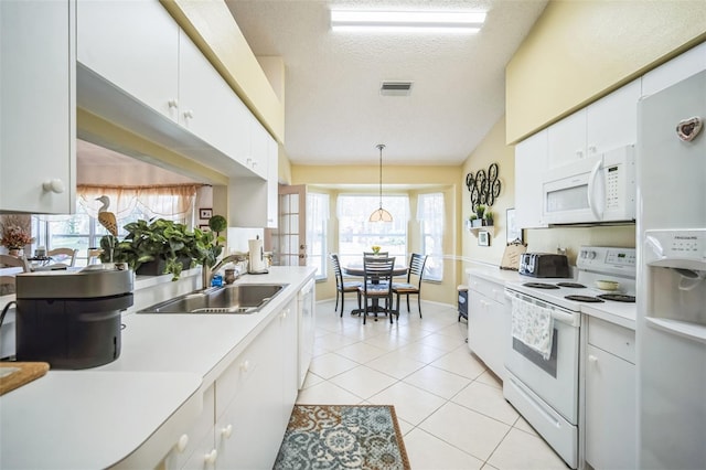 kitchen featuring white appliances, white cabinets, sink, a textured ceiling, and decorative light fixtures