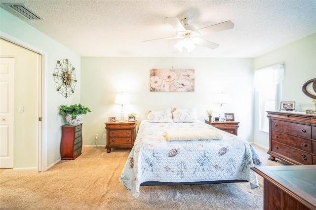 bedroom featuring a textured ceiling, ceiling fan, and light carpet