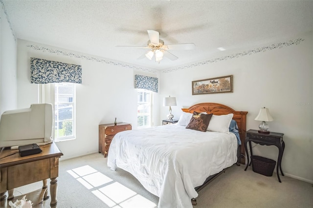 bedroom featuring ceiling fan, light colored carpet, and a textured ceiling