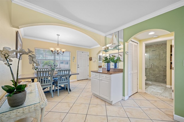 kitchen with ornamental molding, light tile patterned floors, decorative light fixtures, white cabinets, and a chandelier