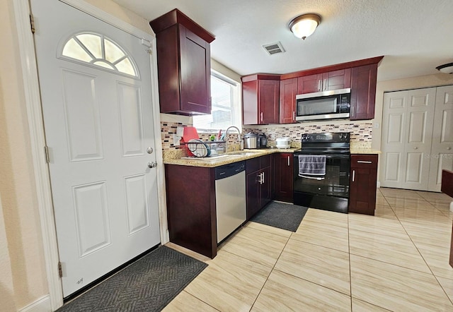 kitchen with decorative backsplash, sink, light tile patterned floors, and stainless steel appliances