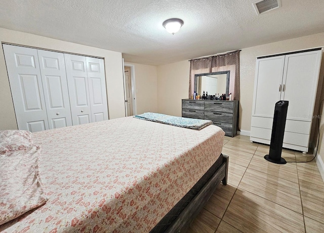 bedroom with light tile patterned floors, a textured ceiling, and two closets