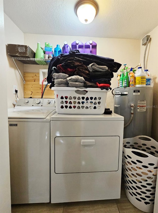 washroom with electric water heater, separate washer and dryer, and a textured ceiling