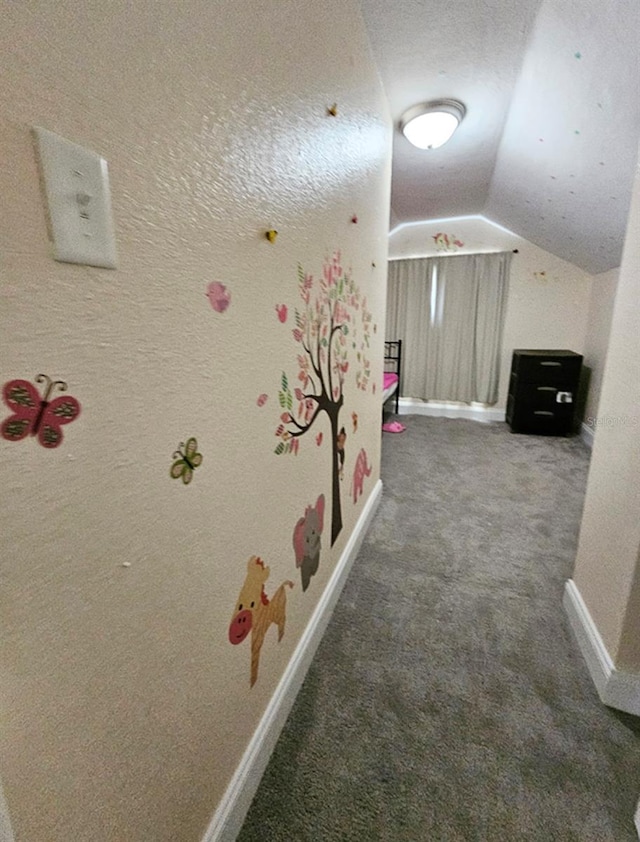 corridor featuring a textured ceiling, vaulted ceiling, and dark colored carpet