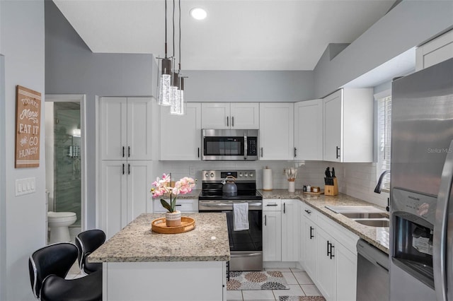 kitchen with a center island, tasteful backsplash, decorative light fixtures, white cabinets, and appliances with stainless steel finishes