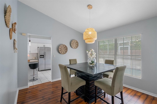 dining area featuring vaulted ceiling and light wood-type flooring