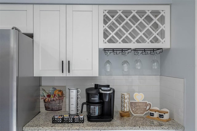 interior space with light stone countertops, white cabinetry, and stainless steel refrigerator