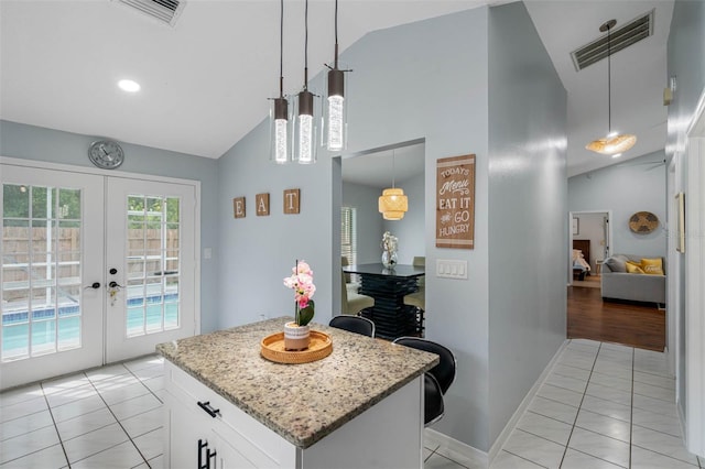 kitchen featuring french doors, light tile patterned floors, decorative light fixtures, white cabinetry, and lofted ceiling