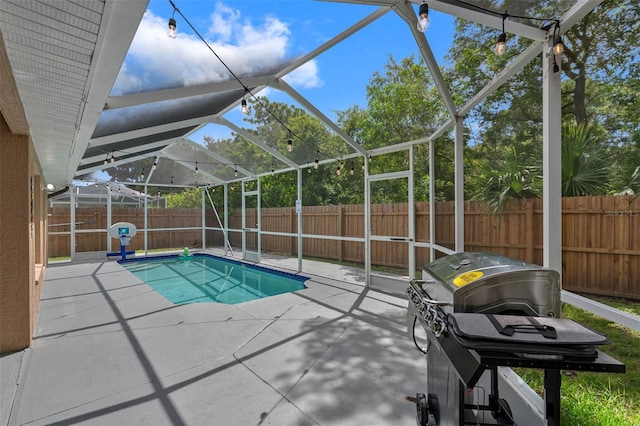 view of pool with a patio, glass enclosure, and a grill