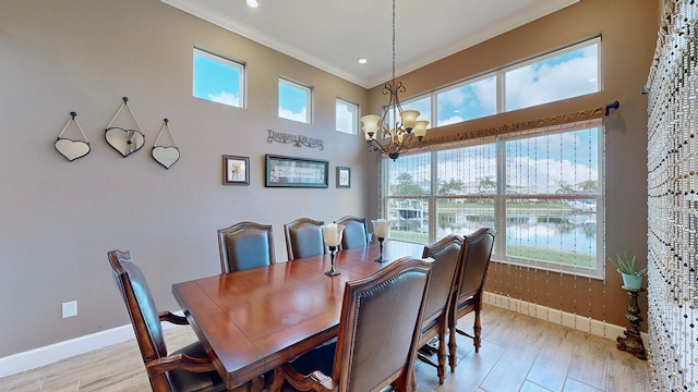 dining area with light hardwood / wood-style flooring, crown molding, and a notable chandelier