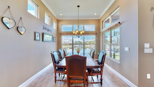 dining space with light hardwood / wood-style flooring, crown molding, and a notable chandelier