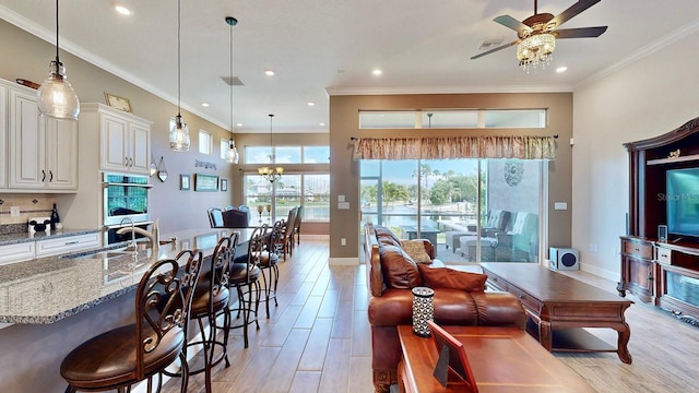 living room featuring ceiling fan, sink, and crown molding