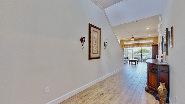 corridor with a high ceiling, light hardwood / wood-style flooring, and crown molding