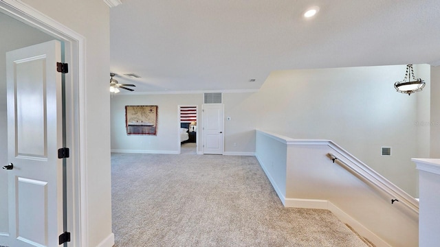 corridor with crown molding and light colored carpet