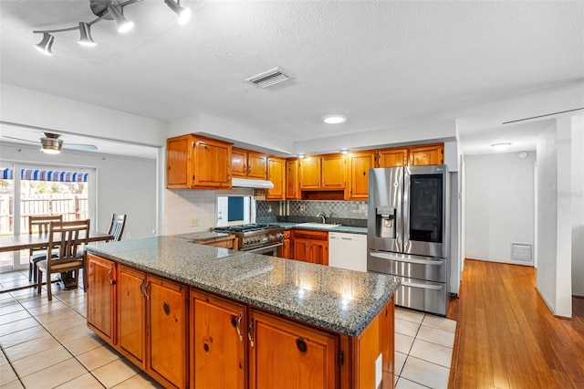 kitchen with ceiling fan, sink, stainless steel appliances, decorative backsplash, and light tile patterned floors