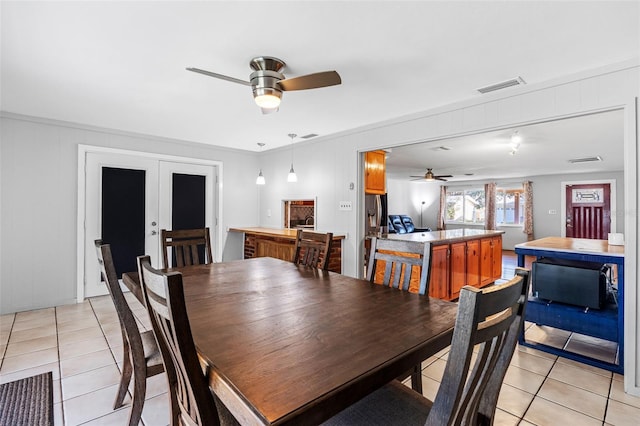 dining room featuring ceiling fan, french doors, light tile patterned floors, and crown molding