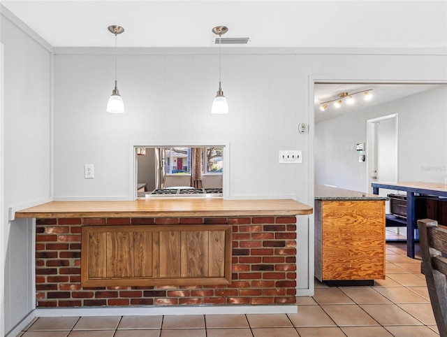 bar with decorative light fixtures, wood walls, stone countertops, and light tile patterned floors