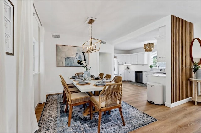 dining area featuring light wood-type flooring and a chandelier