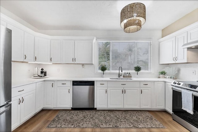 kitchen with white cabinets, sink, stainless steel appliances, and hardwood / wood-style floors