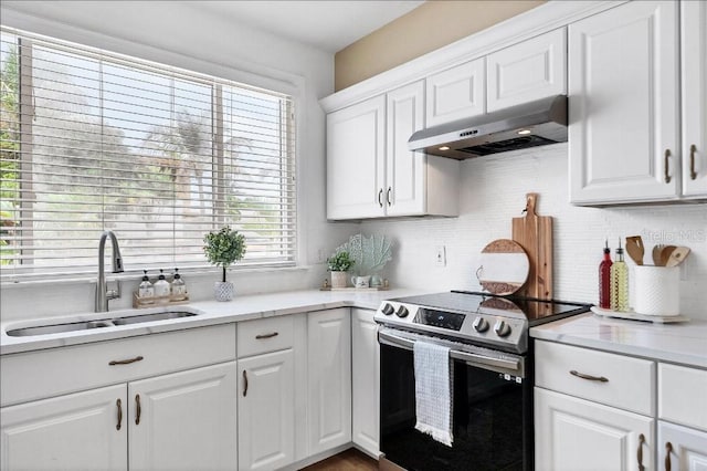 kitchen with stainless steel electric stove, a wealth of natural light, white cabinetry, and sink