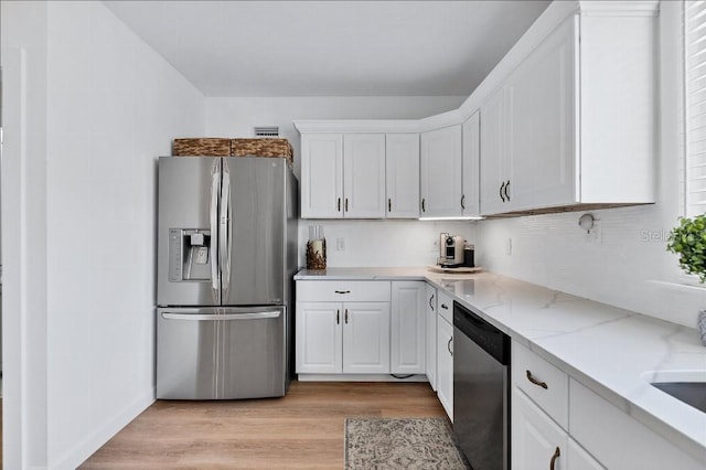 kitchen featuring white cabinets, stainless steel appliances, light hardwood / wood-style flooring, and light stone countertops