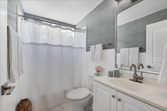 bathroom featuring vanity, tile walls, and toilet