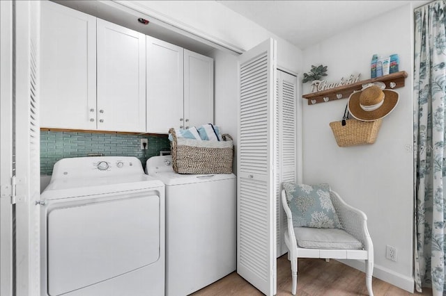 laundry room with washer and clothes dryer, cabinets, and light wood-type flooring