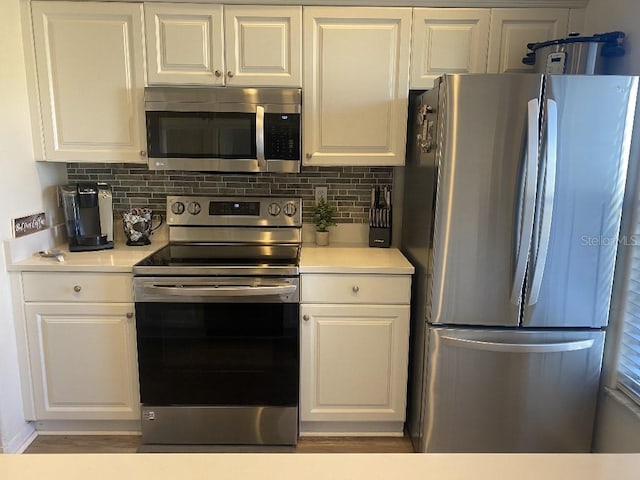 kitchen with appliances with stainless steel finishes, tasteful backsplash, and white cabinetry