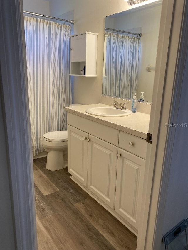 bathroom with a shower with curtain, vanity, wood-type flooring, and toilet