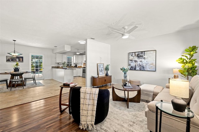 living room with ceiling fan, ornamental molding, and light hardwood / wood-style floors