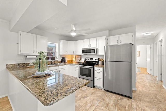 kitchen featuring appliances with stainless steel finishes, stone countertops, sink, white cabinets, and kitchen peninsula