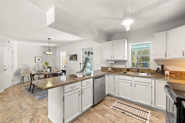 kitchen with sink, white cabinetry, dark stone countertops, appliances with stainless steel finishes, and kitchen peninsula