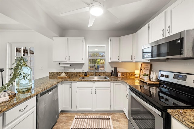 kitchen featuring stainless steel appliances, sink, dark stone counters, and white cabinets