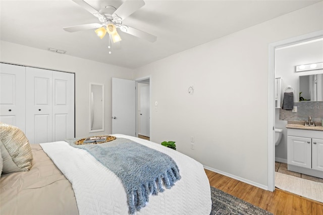 bedroom with sink, hardwood / wood-style flooring, ensuite bath, ceiling fan, and a closet