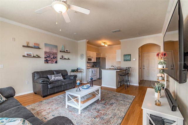 living room with ceiling fan, light hardwood / wood-style floors, and ornamental molding