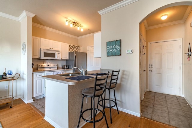 kitchen with kitchen peninsula, range with electric cooktop, sink, white cabinetry, and a breakfast bar area