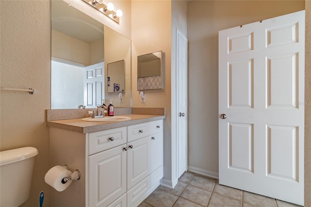 bathroom with tile patterned flooring, vanity, and toilet