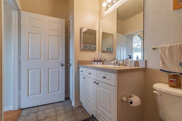 bathroom with tile patterned flooring, ceiling fan, toilet, and vanity