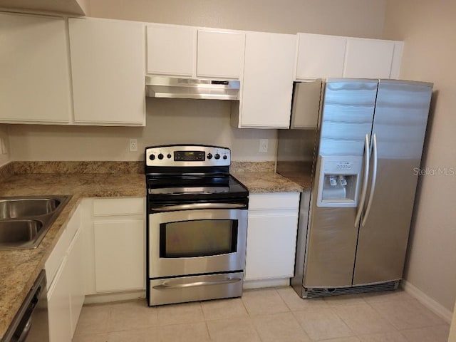 kitchen featuring appliances with stainless steel finishes, sink, light tile patterned floors, dark stone countertops, and white cabinetry