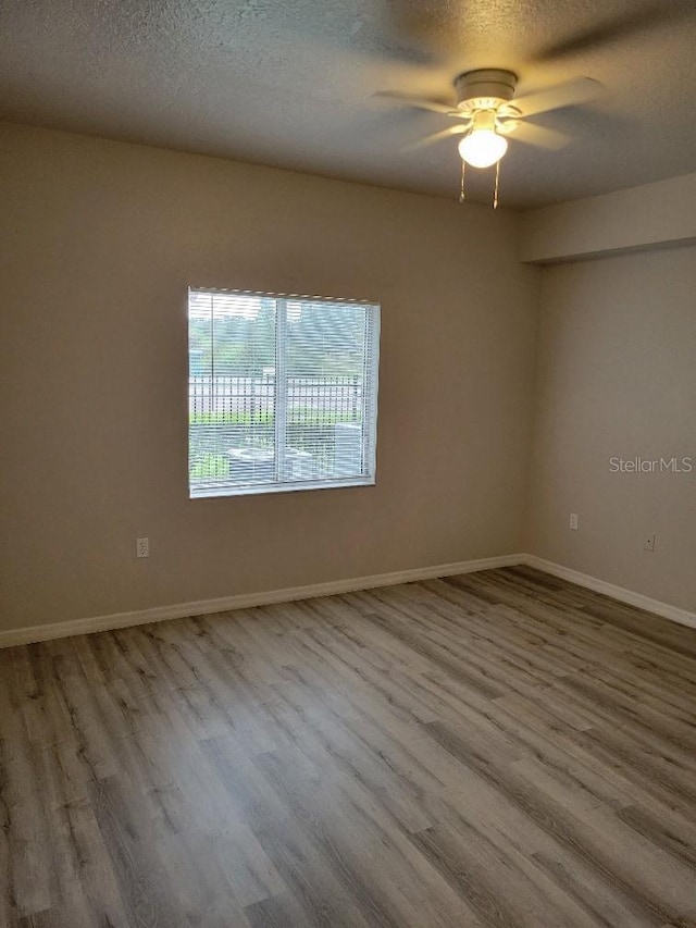 empty room with ceiling fan, a textured ceiling, and hardwood / wood-style flooring