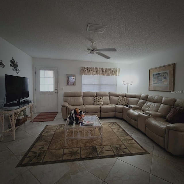 living room featuring ceiling fan, light tile patterned floors, and a textured ceiling