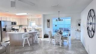 kitchen featuring appliances with stainless steel finishes, a breakfast bar, decorative light fixtures, an inviting chandelier, and a center island