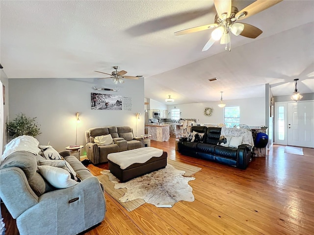 living room featuring ceiling fan, light hardwood / wood-style floors, and lofted ceiling