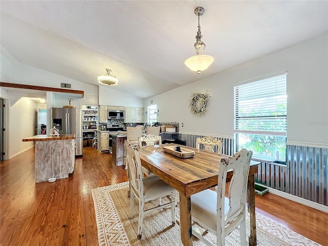 dining space with light hardwood / wood-style floors and lofted ceiling