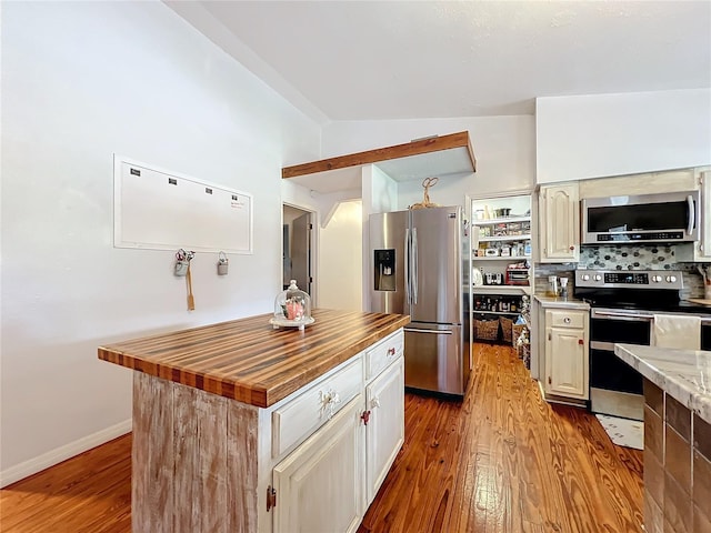 kitchen featuring a center island, stainless steel appliances, tasteful backsplash, light hardwood / wood-style floors, and lofted ceiling