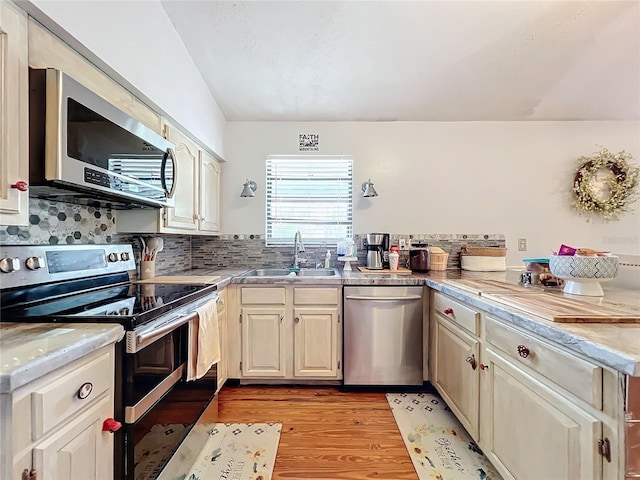 kitchen featuring backsplash, sink, stainless steel appliances, and light hardwood / wood-style flooring